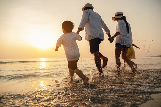 A happy family walking together on the beach at sunset