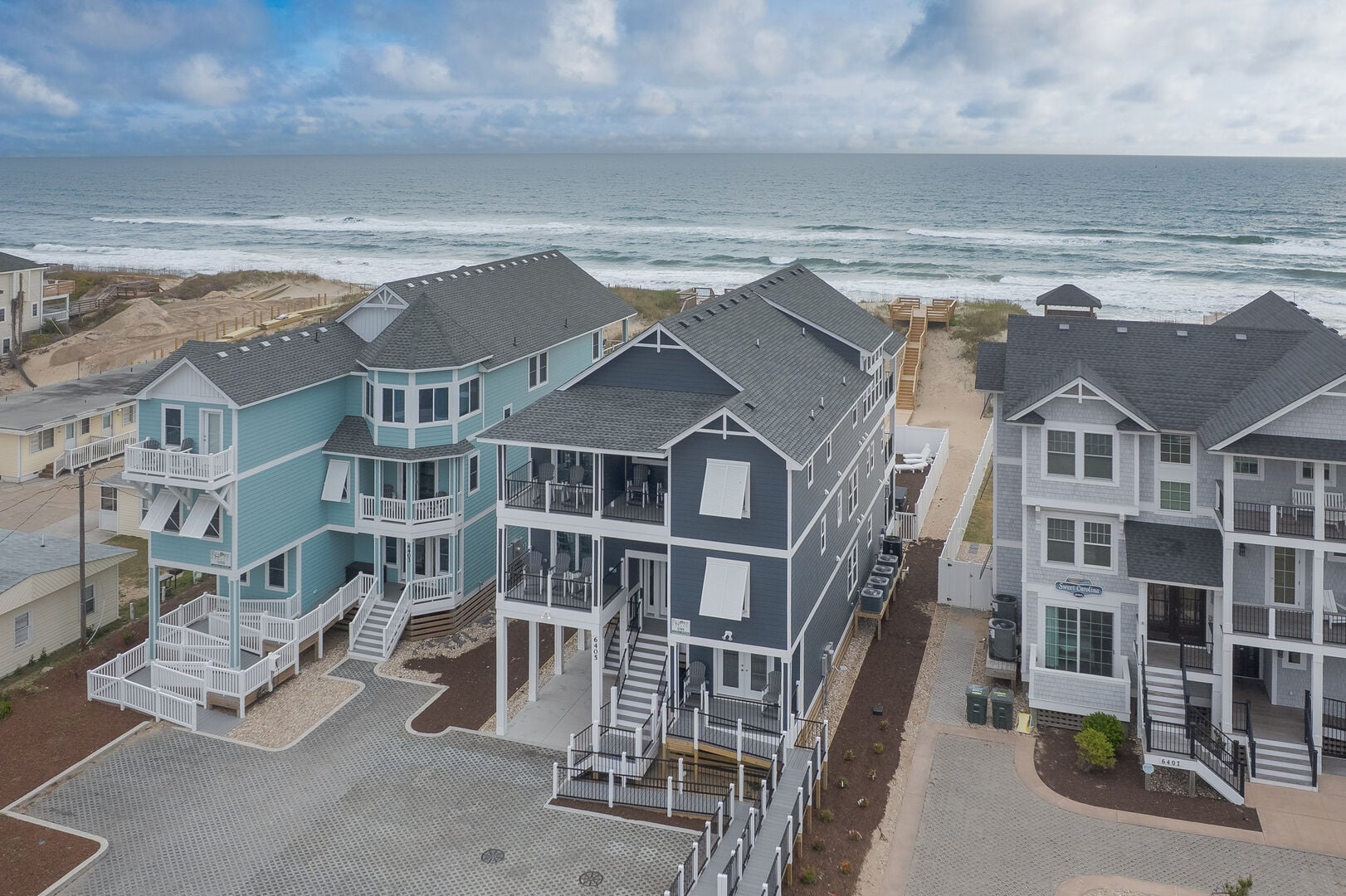 Multi-story oceanfront beach house with a top-level deck at golden hour