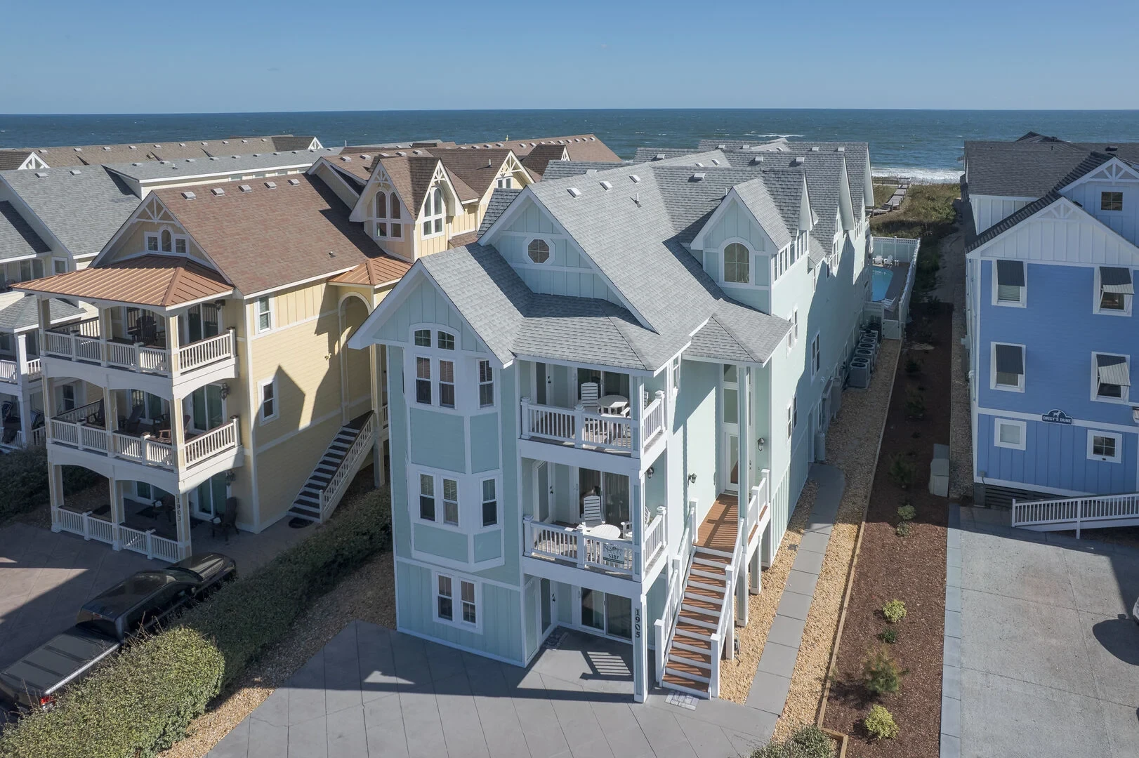 Aerial view of multi-story oceanfront beach houses on stilts along the shore